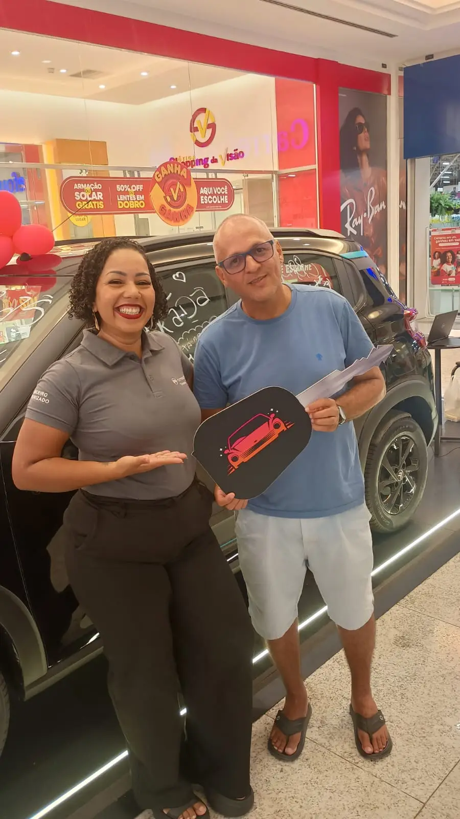 Consultora da ABA e cliente segurando a chave cenográfica ao lado de um Citroën preto