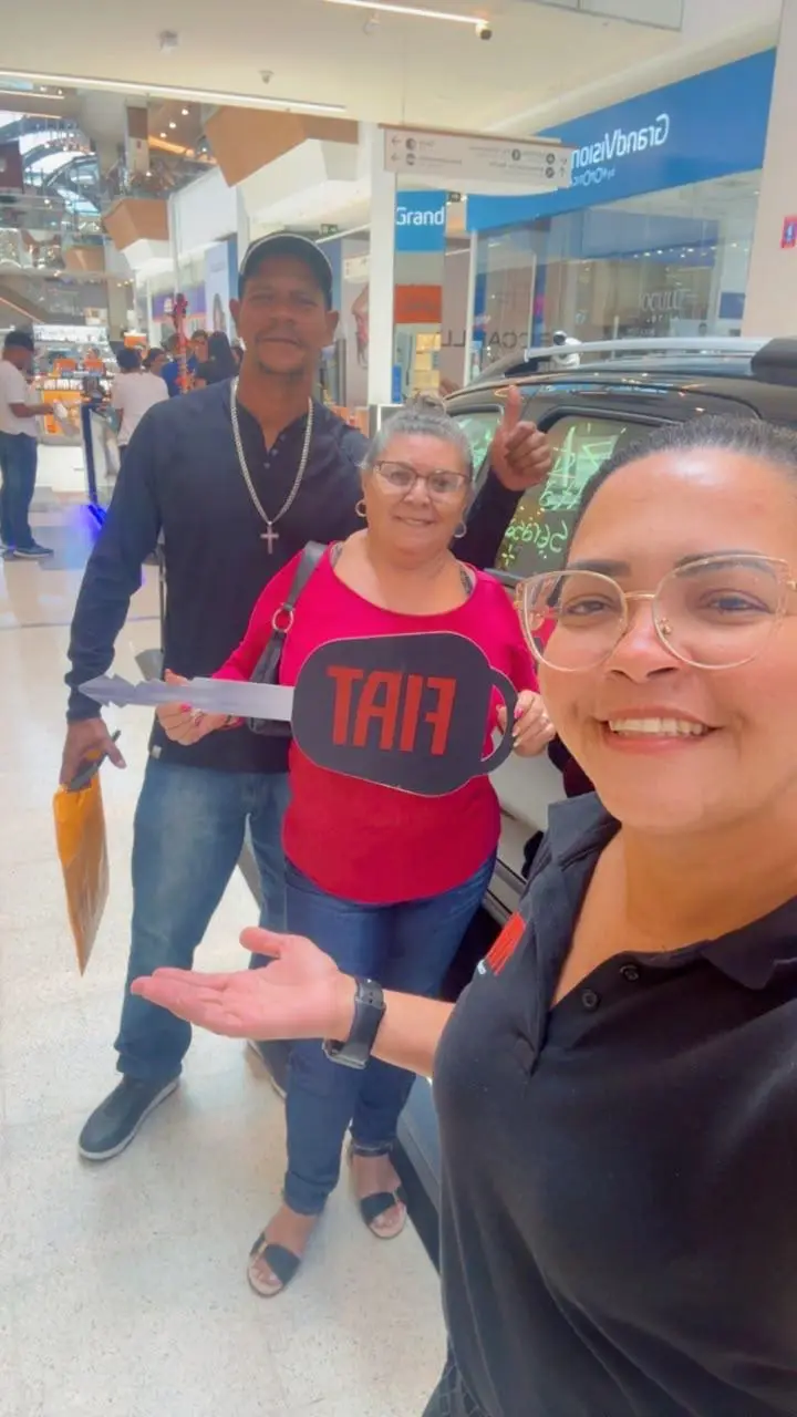 Consultora da ABA em selfie com clientes segurando a chave Fiat