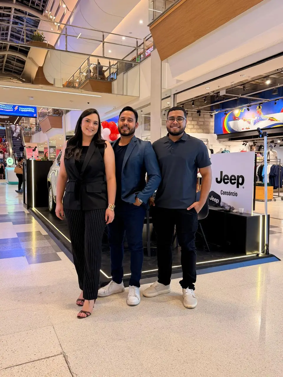 Integrantes da ABA Consórcios em frente ao stand no shopping, com o carro em exposição